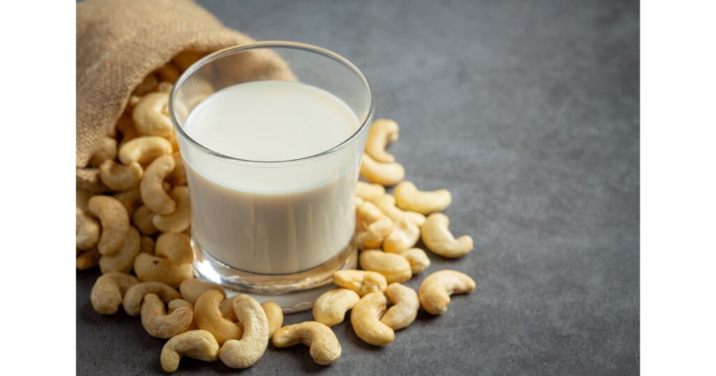 vegan cashew milk glass with cashews nuts dark background